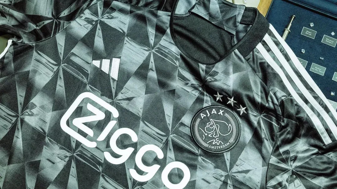 Gros plan sur le tissu et l'écusson brodé d'un maillot de football gris